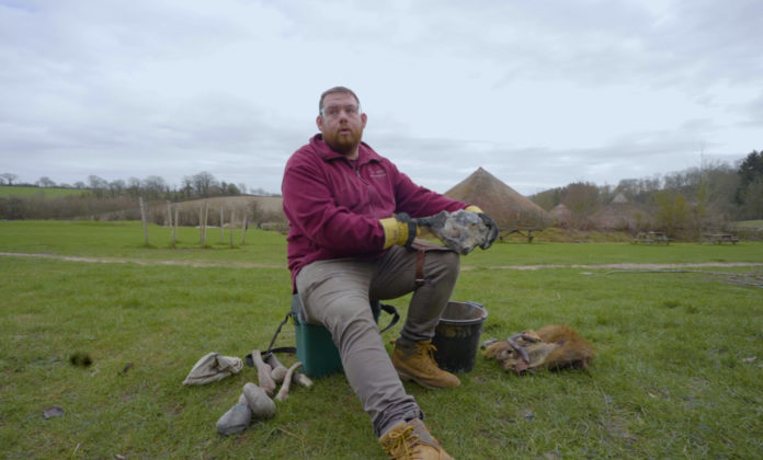 Mark sits and scrapes flint into Stone Age tools